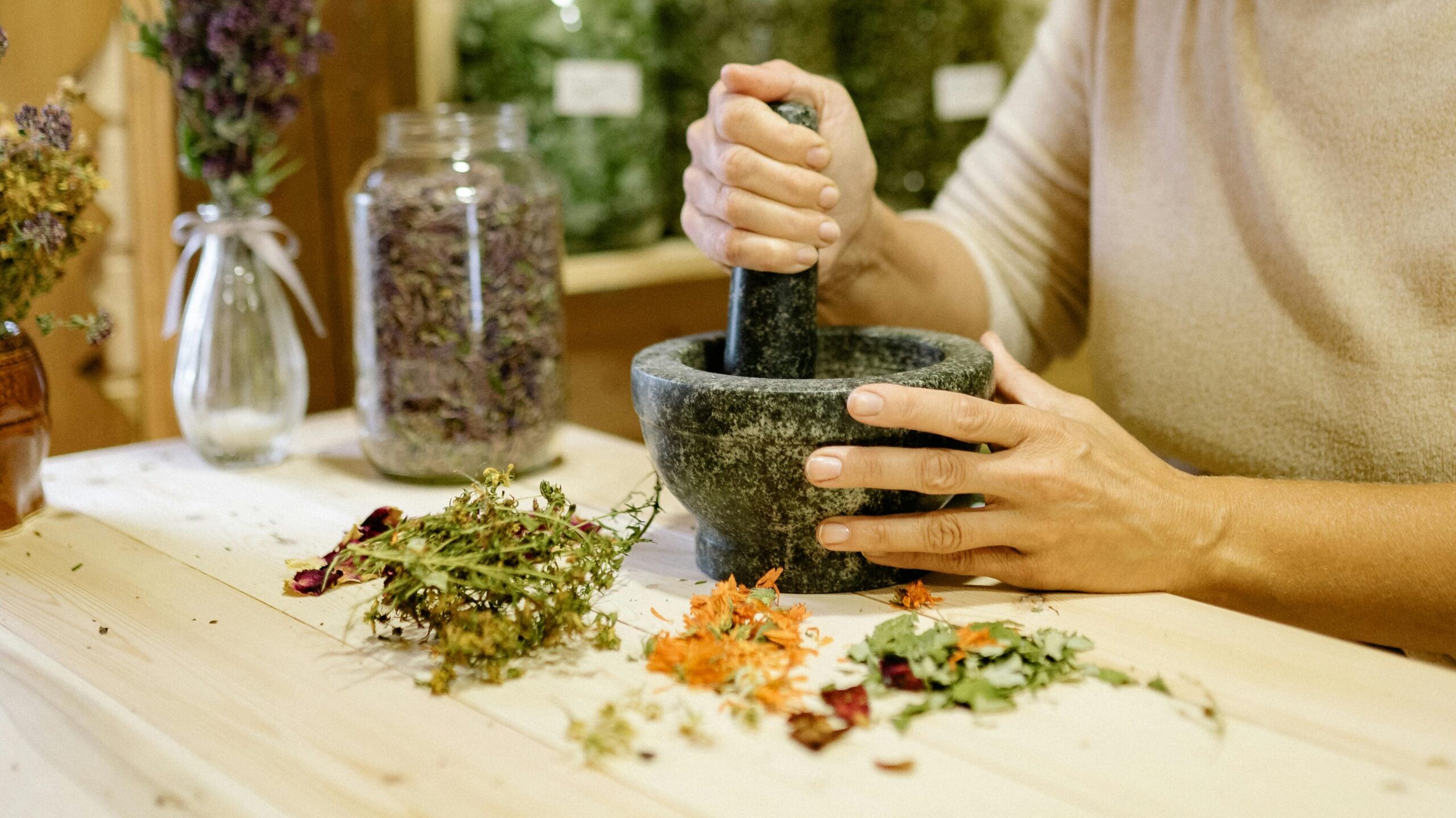 A woman uses a mortar and pestle to prepare natural herbal remedies indoors.
