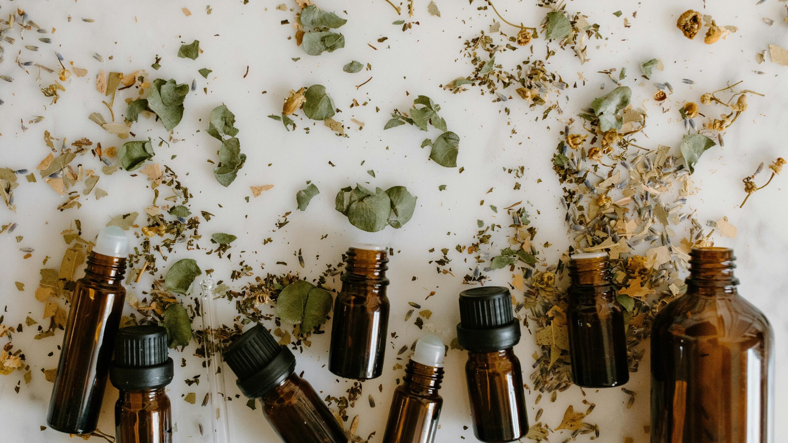 Flat lay of brown glass bottles and dried herbs, perfect for aromatherapy themes.