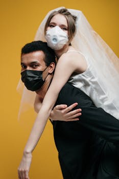 A bride and groom wearing masks embrace in a playful pose, symbolizing love during the pandemic.