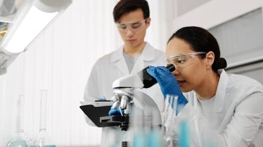 Two scientists in a laboratory using a microscope and analyzing samples.